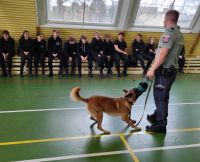 Funkcjonariusz z psem i klasy mundurowe na sali gimnastycznej
