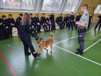 Funkcjonariusz z psem i klasy mundurowe na sali gimnastycznej