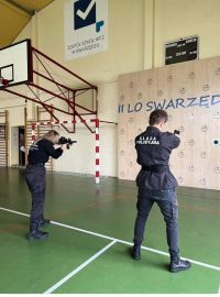 Uczniowie trzymają broń i strzelają do celu
