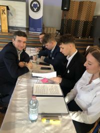 Uczniowie siedzący przy stole przygotowujący się do debaty